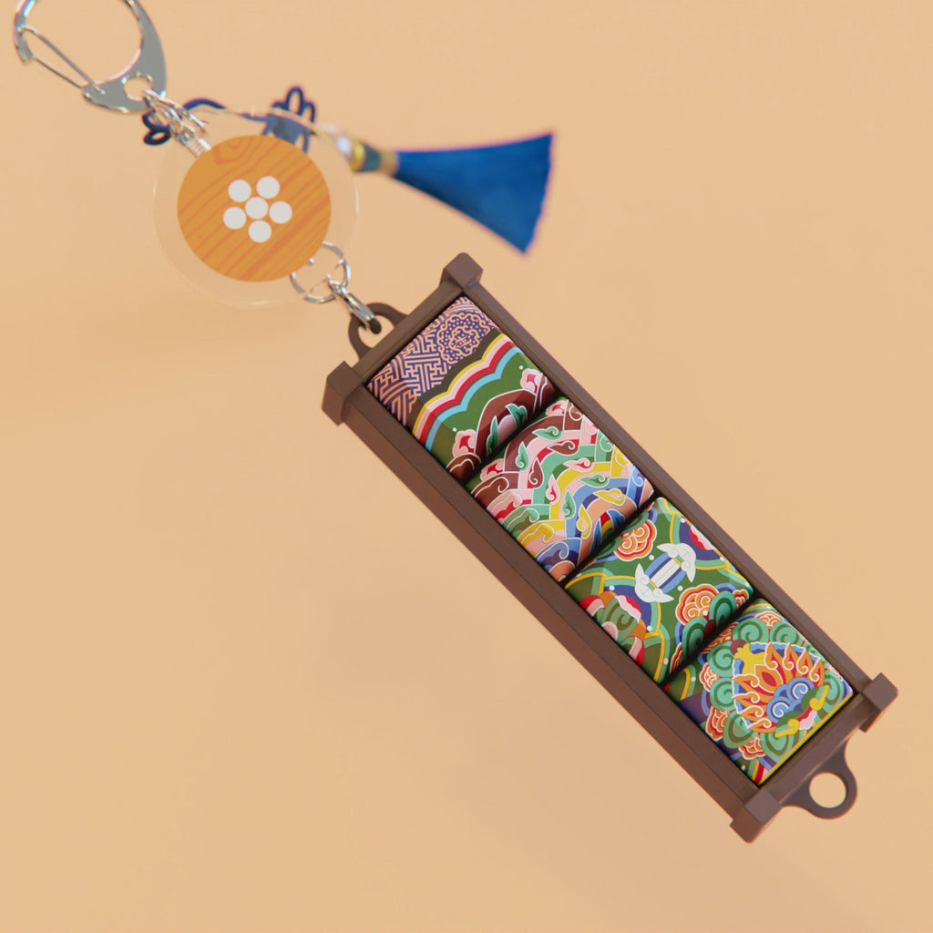 Gyotaejeon Dancheong keycap keychain and round charm on a beige surface