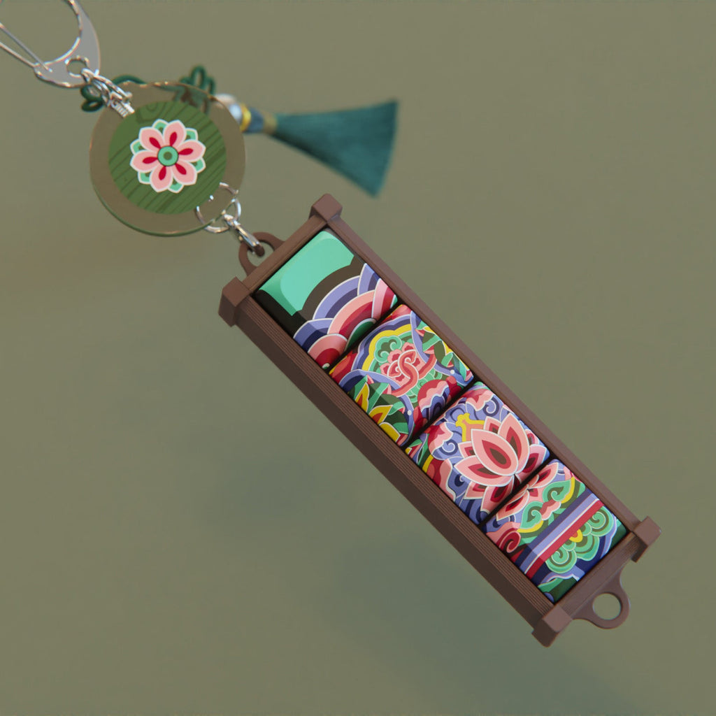 Black Dancheong keycap keychain and round charm laid flat on a dark green surface